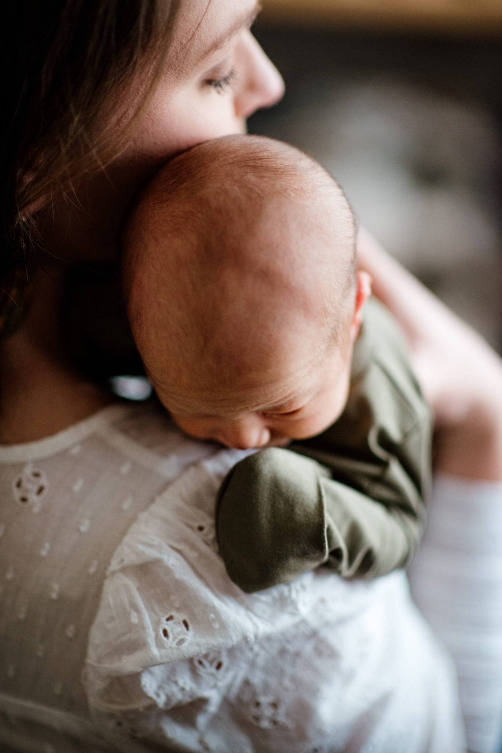 newborn baby held on moms shoulder