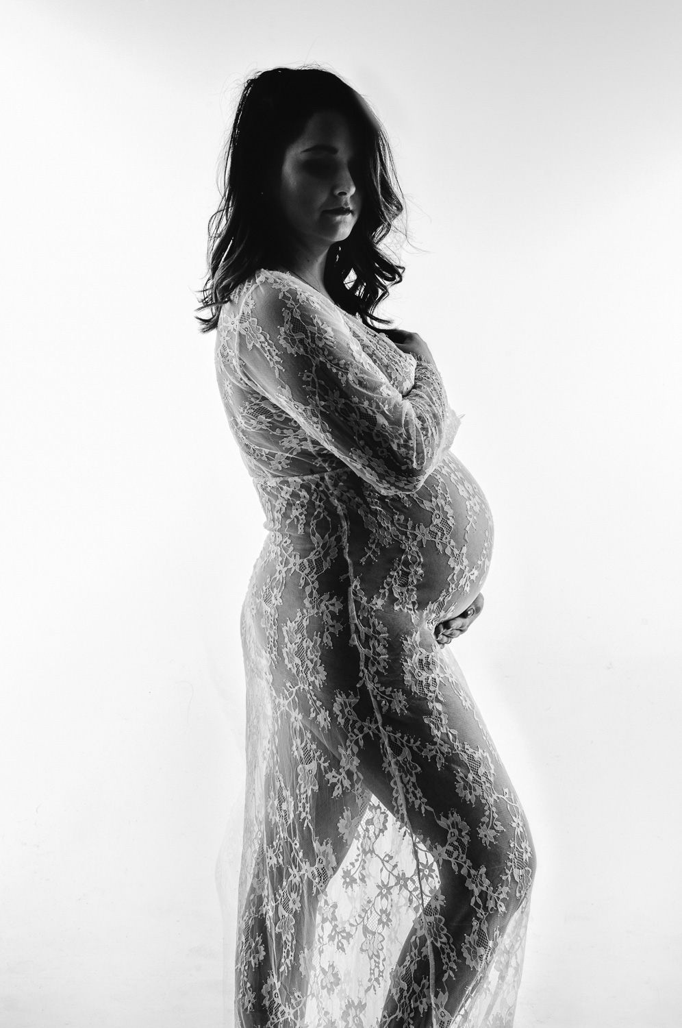 pregnant woman in sheer lacy gown white background