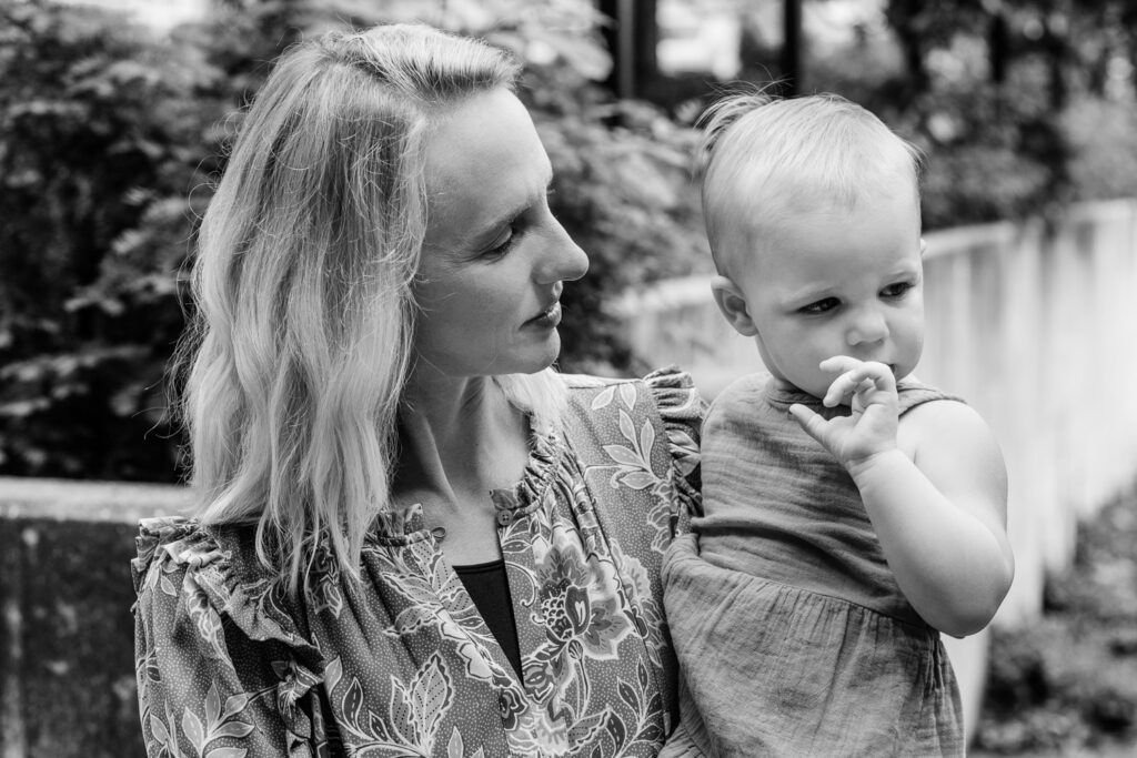 Mother looks at young daughter in her arms.