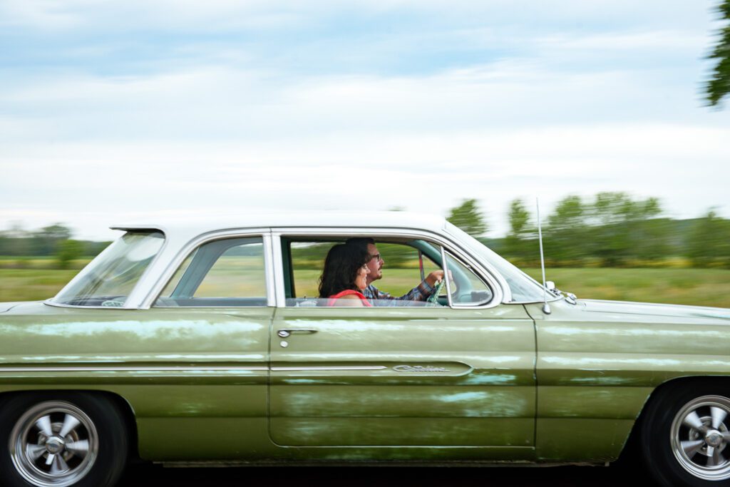 Couple driving green car on highway.
