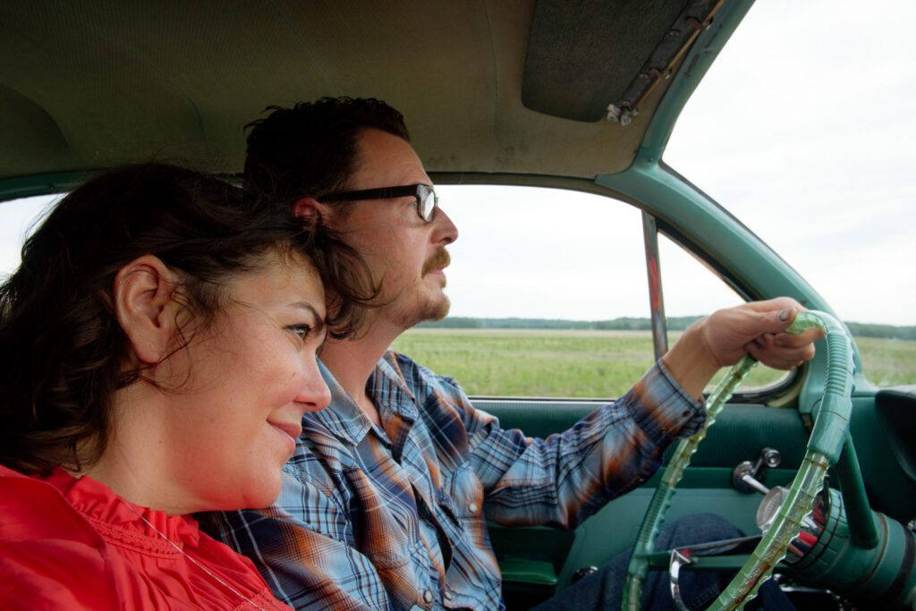 Couple's hair blows in wind while driving car