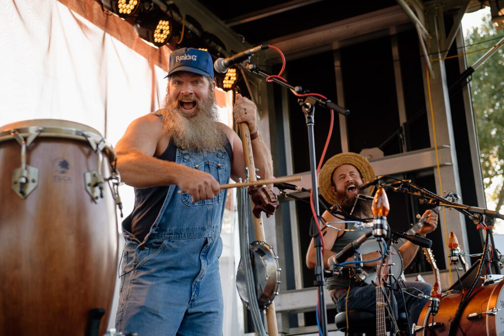 Man wearing overalls strumming guitar