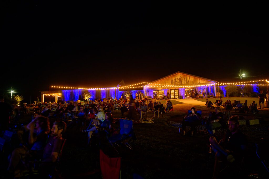 crowd sits under lights at coopers ridge event venue