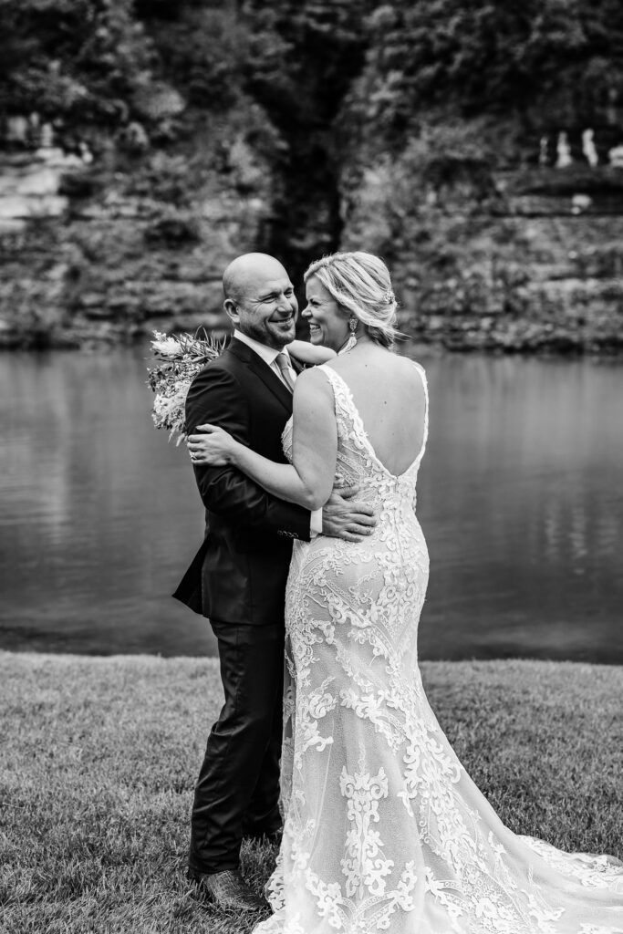 Bride and Groom smile and laugh near creek and cliff