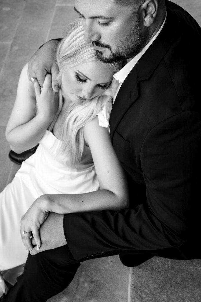 Couple holding hands and snuggling together on steps.