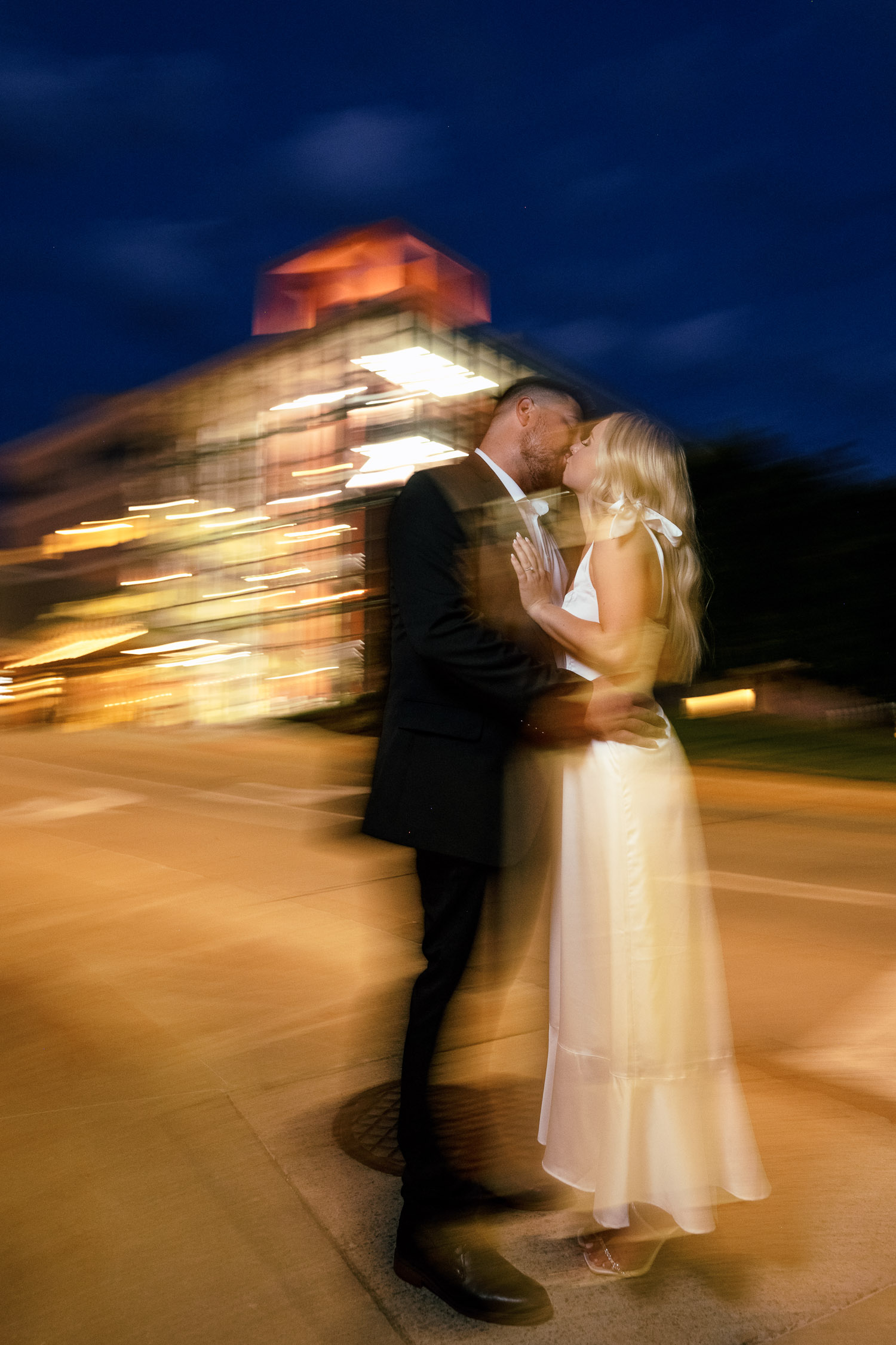 Dragged shutter portrait of couple kissing at night time engagement session