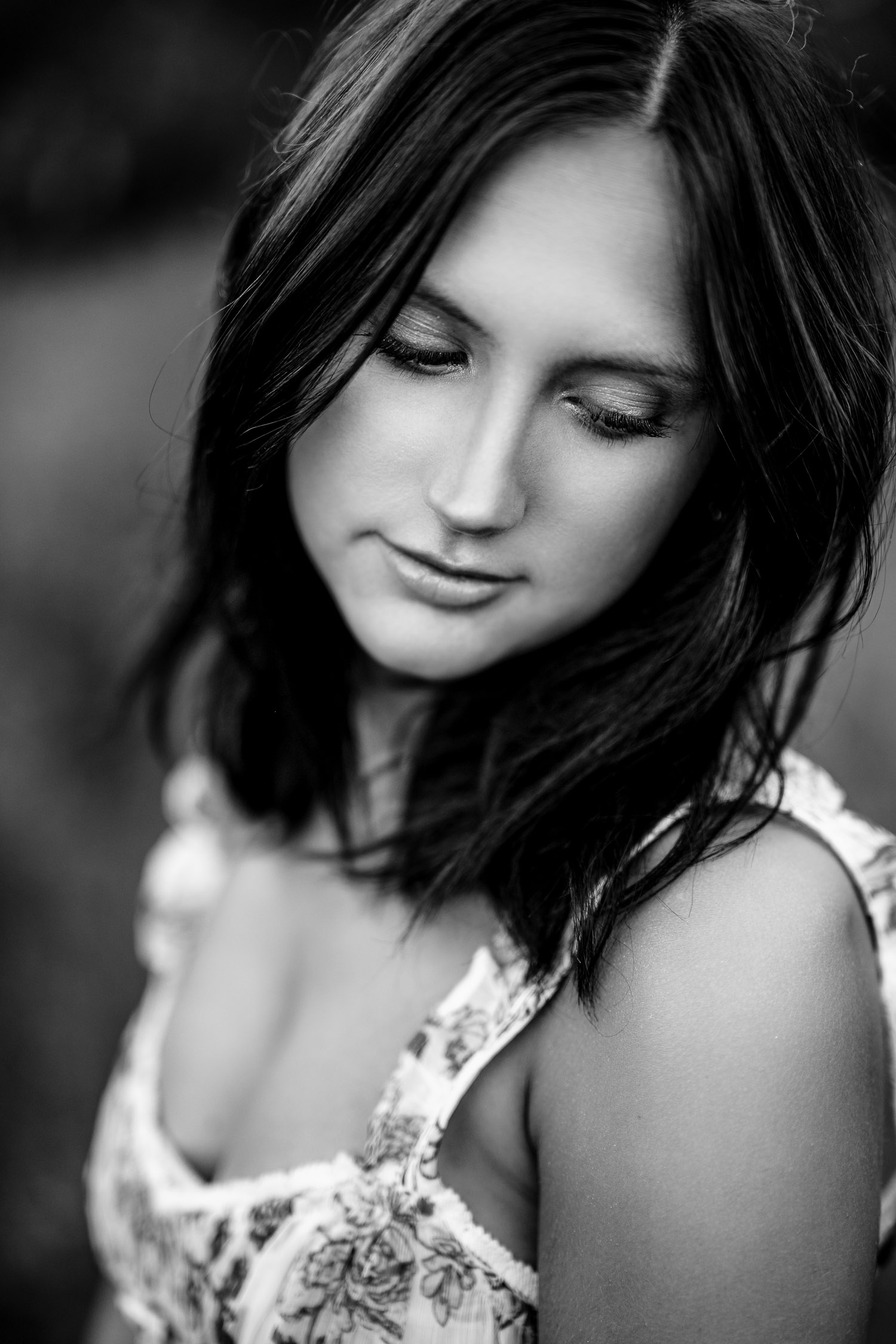 Black and white image of brunette senior girl looking down her shoulder.