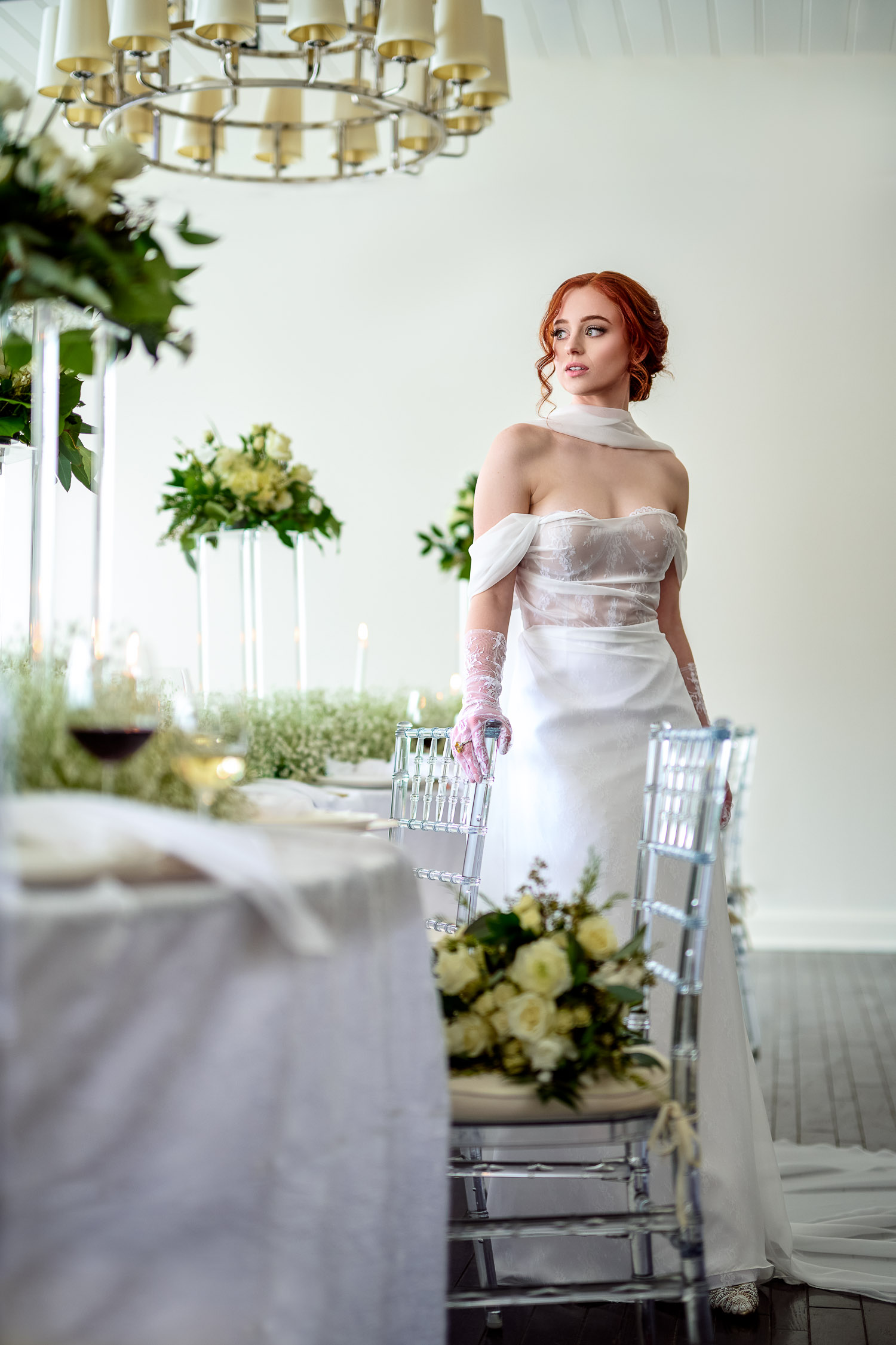 Bride stands next to s curve table with acrylic chairs and baby breath flowers.