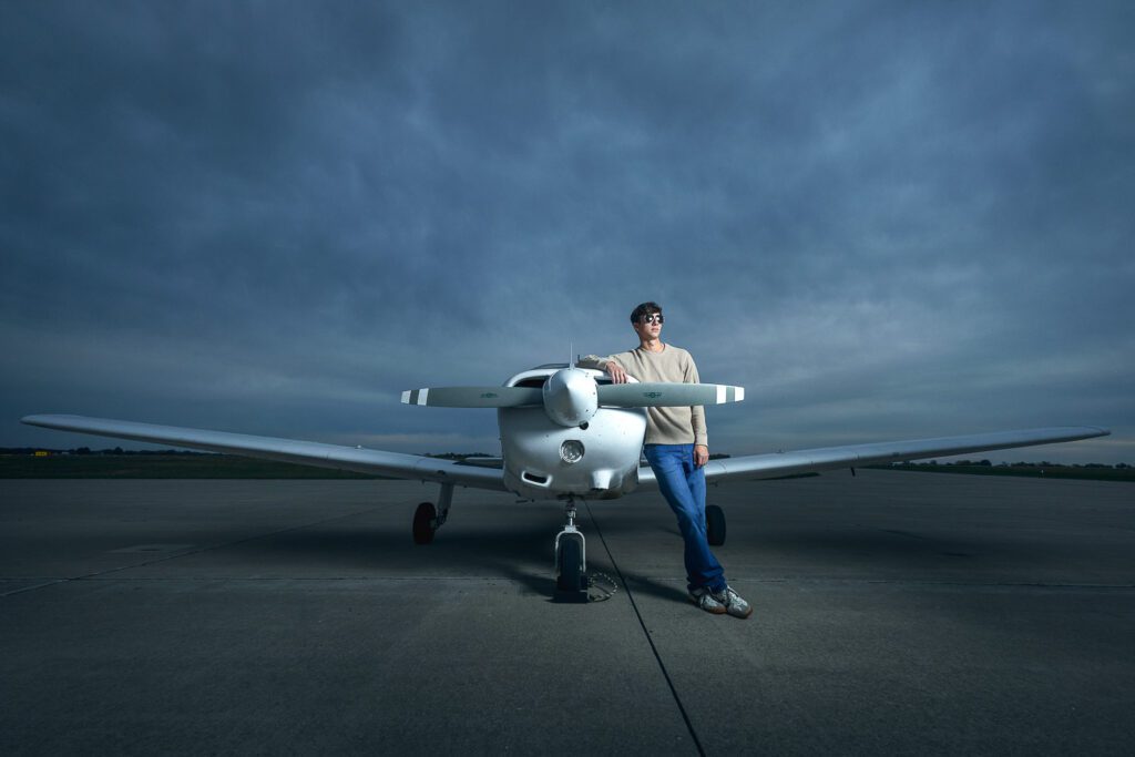 Senior boy leans on propeller of airplane
