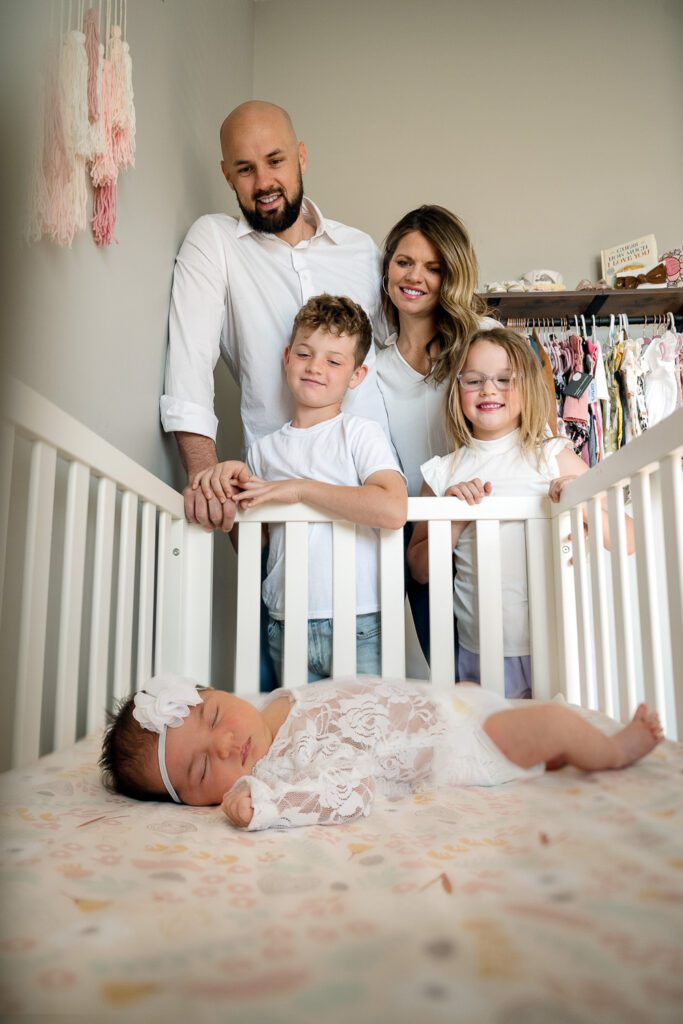 family looks at newborn baby girl in crib