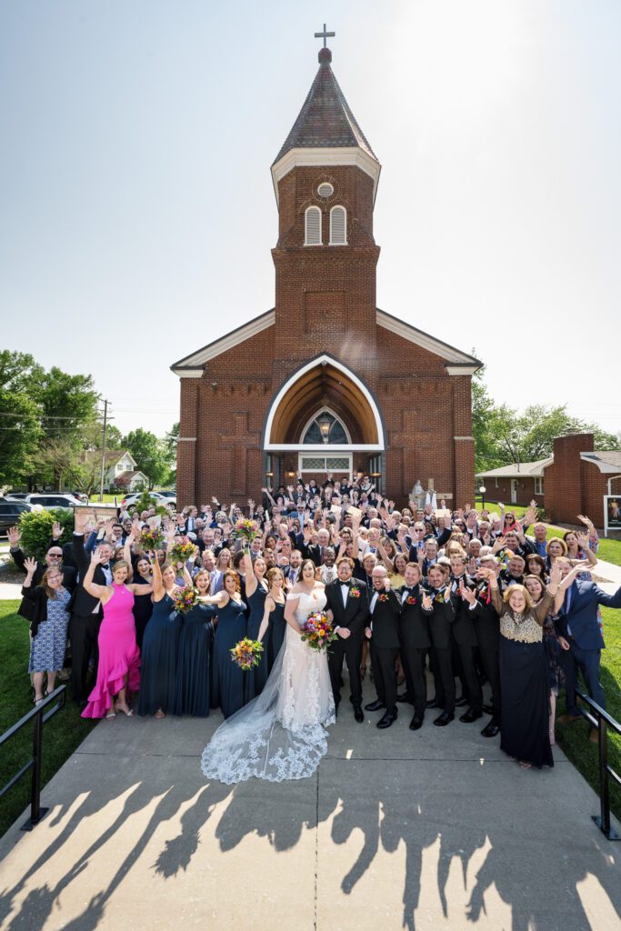 large group of people stand in front of montgomery city catholic church after wedding ceremony