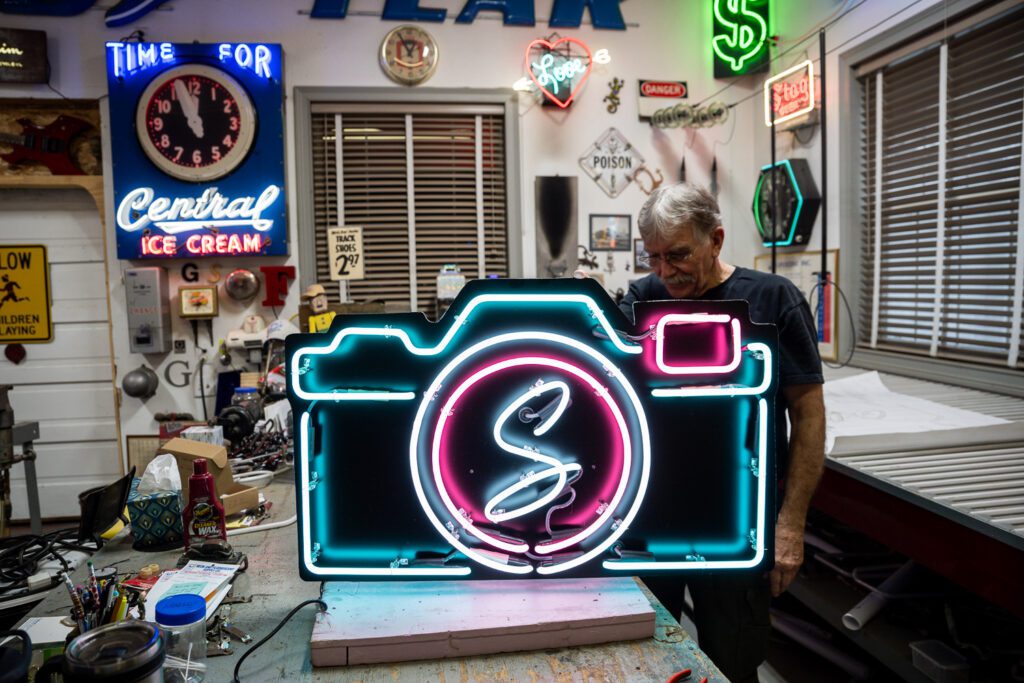 Jim McCarter holds up Schaefer Photography Neon Sign he created.