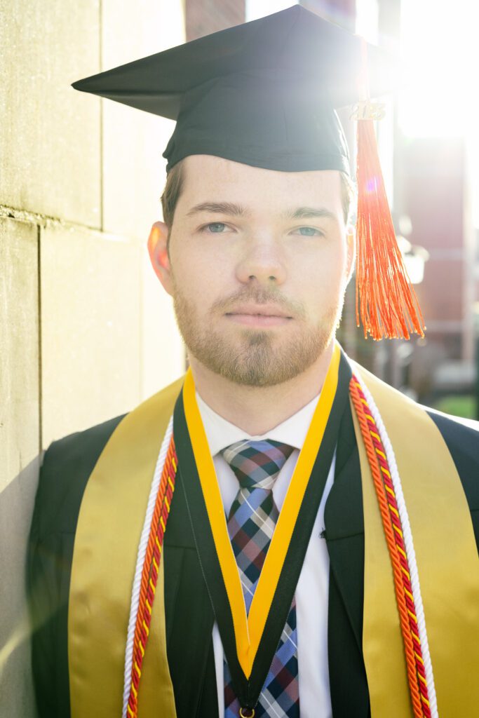 white senior guy wearing cap and gown with sunshine